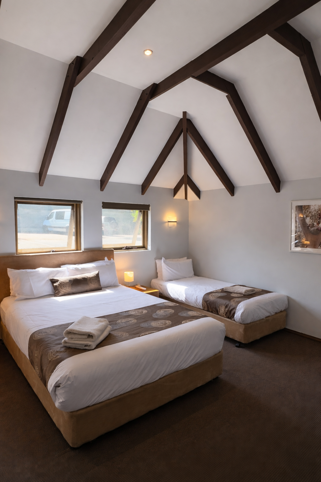 Family room with king bed and single bed under vaulted timber ceilings
